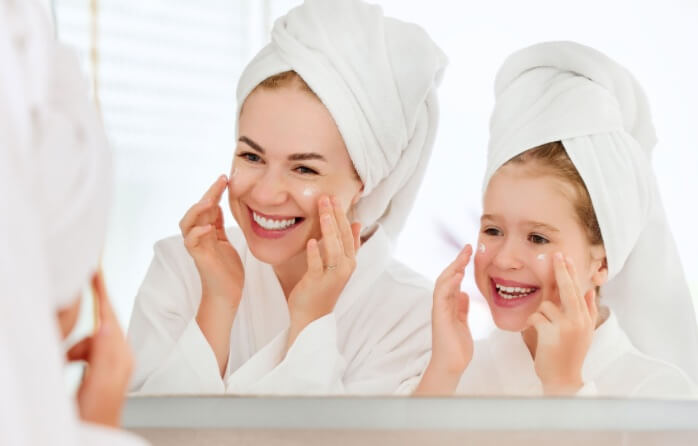 happy mother and daughter doing skincare